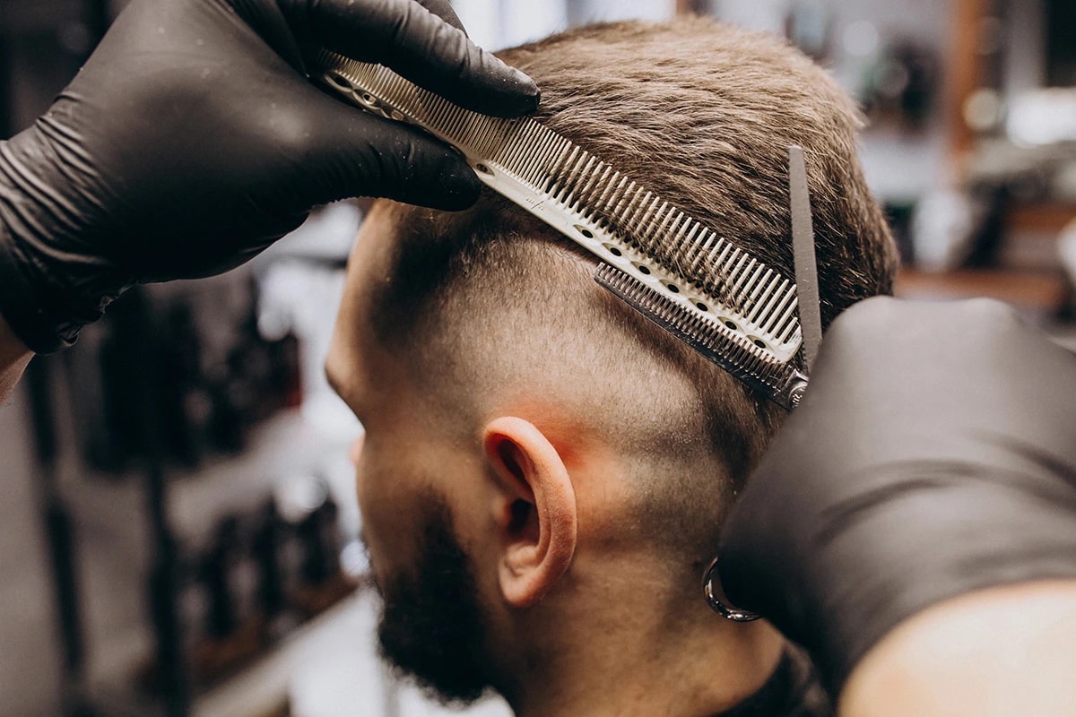 Barbero trabajando un corte de cabello con tijera y peine